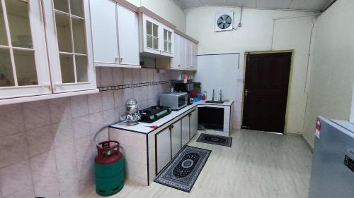 uma pequena cozinha com armários brancos e um fogão em Nik Legacy Homestay em Pasir Puteh