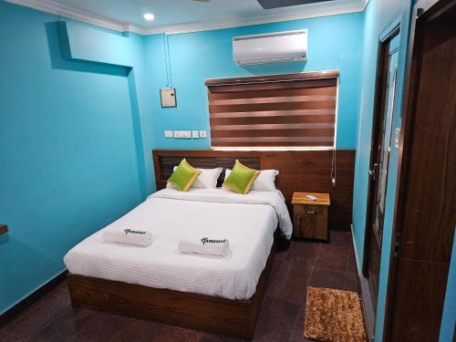 a blue bedroom with a bed with two pillows at Hamsted in Kottakkal