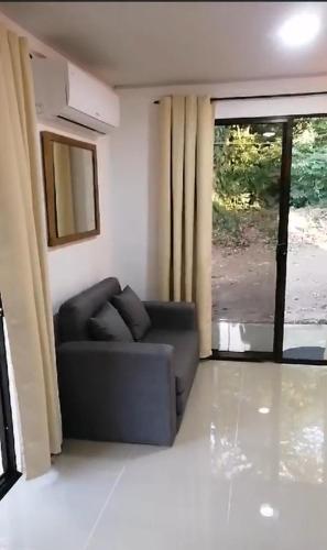 a living room with a couch and a large window at Cabañas Mantas in Tarcoles