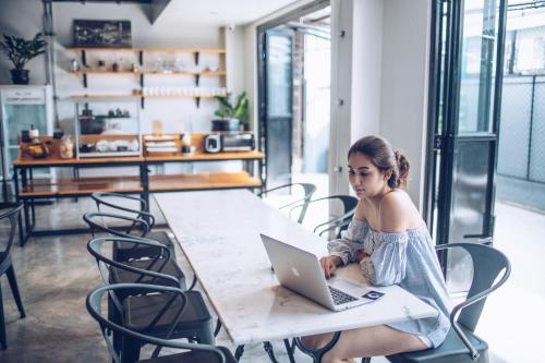 a woman sitting at a table using a laptop computer at Blu Monkey Hub & Hotel Surat Thani in Surat Thani