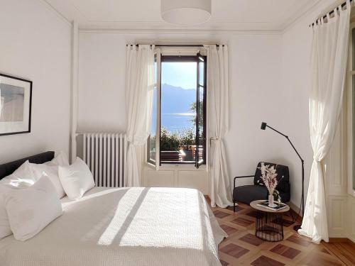 a white bedroom with a bed and a window at Montreux Luxury Suite in Montreux