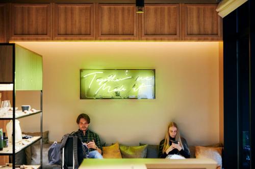 a man and woman sitting on a couch with their cell phones at NOHGA HOTEL AKIHABARA TOKYO in Tokyo