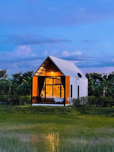 a small house with a large window in a field at Whitehouse resort in Ban Muang Chum