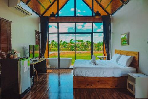 a bedroom with a bed and a large window with a tub at Whitehouse resort in Ban Muang Chum