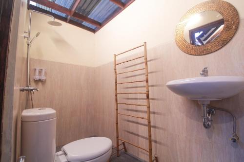 une salle de bain avec toilettes, lavabo et miroir dans l'établissement Omah Jombor Homestay Jogja, à Kejayan