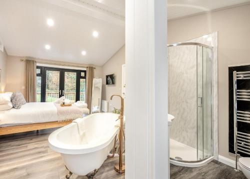 a bathroom with a tub and a bedroom with a bed at Charlesworth Lodges in Glossop
