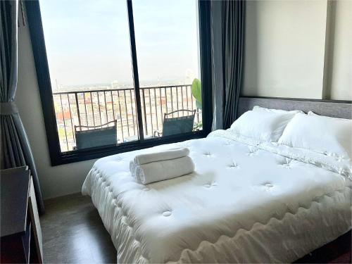Sea view Pattaya beach @The Base Central Pattaya في باتايا سنترال: سرير أبيض في غرفة مع نافذة كبيرة