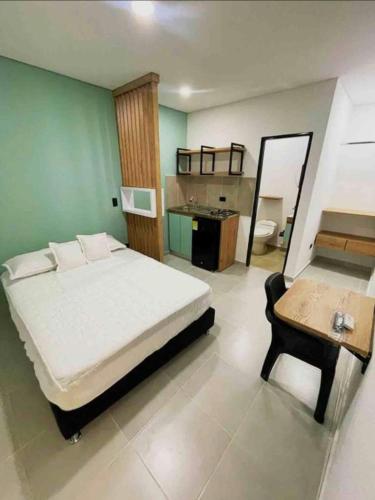 a bedroom with a bed and a table and a bathroom at Hotel La Central Belalcazar Palmira in Palmira