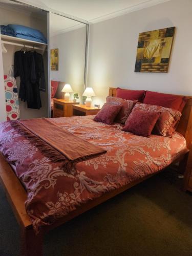 a bedroom with a large bed with red sheets and pillows at Taylor Cottage 