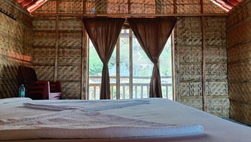 un letto in una camera con una grande finestra di Osho's Organic Resort Hampi a Hampi