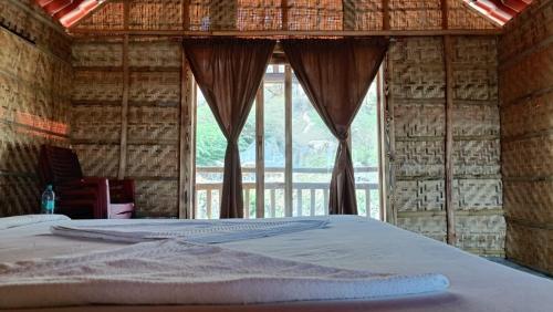 a bed in a room with a large window at Osho's Organic Resort Hampi in Hampi