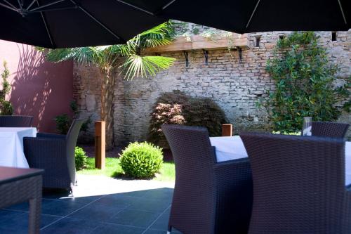 a patio with a table and chairs with an umbrella at Hotel Restaurant Spa Ivan Vautier in Caen