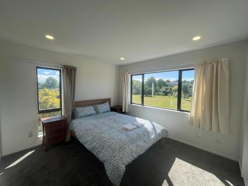 um quarto com uma cama e uma grande janela em Modern Home by the Reserve em Auckland