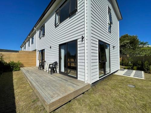 オークランドにあるModern Home by the Reserveの木製デッキ(椅子2脚付)が備わる家