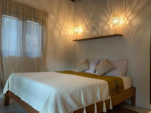 ein Schlafzimmer mit einem Bett mit zwei Lichtern an der Wand in der Unterkunft Keladi Villa in Gili Trawangan
