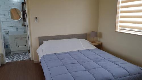 ein Schlafzimmer mit einem Bett mit einer blauen Decke darauf in der Unterkunft Sopoong in Jeju-do