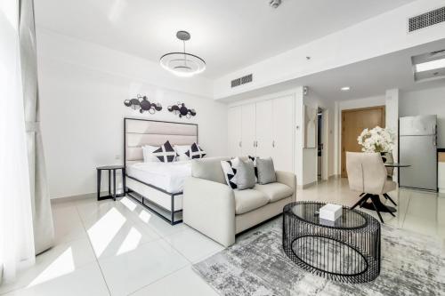 a white bedroom with a bed and a couch at Primestay - Park Central Studio - Business Bay in Dubai
