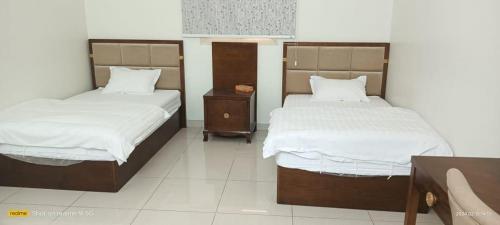 two beds sitting in a room with at فندق رفال الغربية للشقق المخدومة in Ukaz