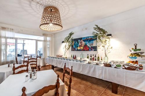 a restaurant with white tables and chairs and a chandelier at Galaxia Boutique Hotel in Can Picafort