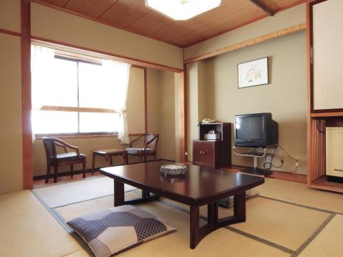 a living room with a coffee table and a tv at Shiga Kogen Lodge in Yamanouchi