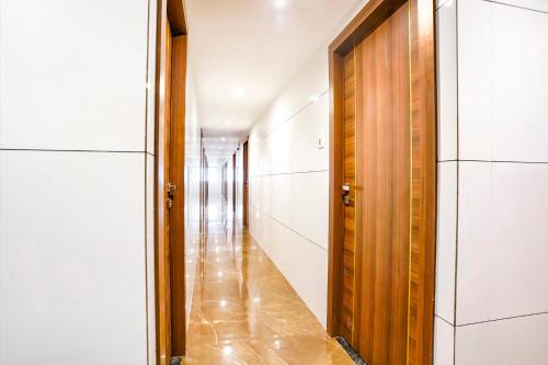 a hallway with a wooden door and white walls at FabHotel Shubham Inn - Nr Jain Mandir, Bhandup West in Mumbai