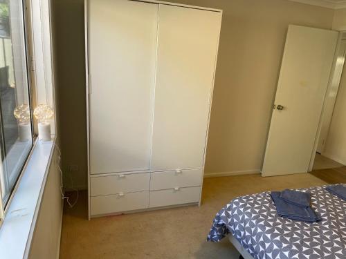 a bedroom with a bed and a large white cabinet at Comfy Newly Furnished Queen bedroom in Point Cook