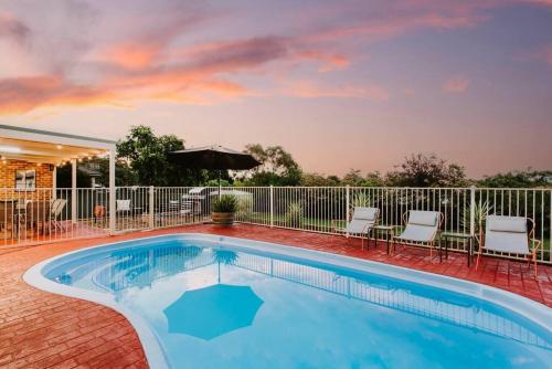 a swimming pool with chairs and an umbrella at Macquarie Manor - Experience Grand Country Living in Mudgee