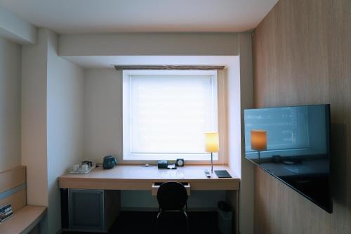 a room with a desk with a window and a monitor at KOKO HOTEL Sendai Kotodai Park in Sendai