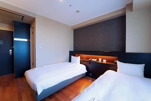 2 letti in una camera d'albergo con 2 letti sidx sidx di KOKO HOTEL Sendai Kotodai Park a Sendai
