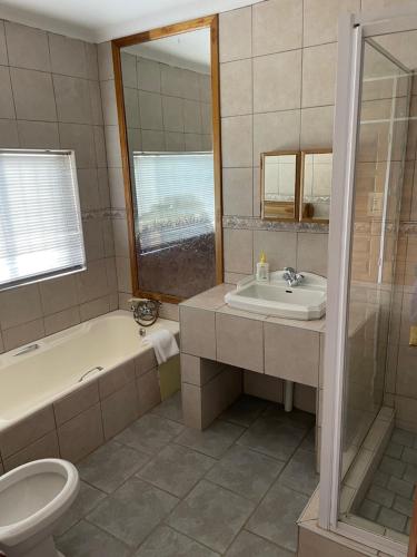 a bathroom with a sink and a tub and a toilet at Eagles View Kungwini in Erasmus