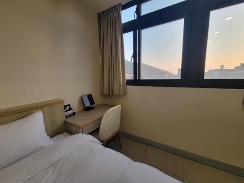 1 dormitorio con cama y escritorio con ventana en 悠而行旅 en Nangan