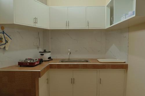 una cocina con armarios blancos y fregadero en Point Vista Transient Accomodation, en Daet