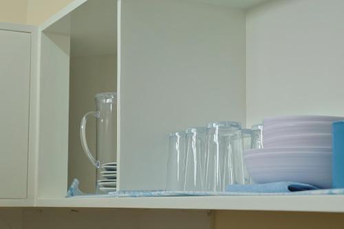 un armario lleno de vasos y platos en un estante en Point Vista Transient Accomodation en Daet