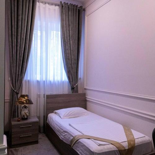 a small bedroom with a bed and a window at OA Tashkent in Qŭyliq