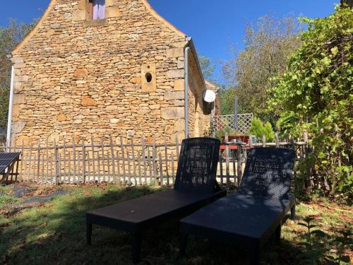 duas cadeiras e um banco em frente a um edifício de pedra em Grange restaurée à la campagne em Tamniès