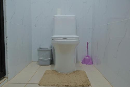 a bathroom with a toilet with a rug and a broom at Point Vista Transient Accomodation in Daet