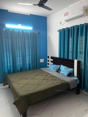 a bedroom with blue walls and a bed with blue curtains at Vacation Guest House in Trivandrum
