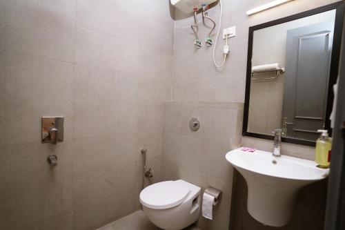 y baño con aseo, lavabo y espejo. en Hotel Lyf Corporate Suites Meera Bagh en Nueva Delhi