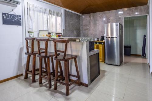 a kitchen with a bar with stools and a refrigerator at Casa kattleya in Tortuguero