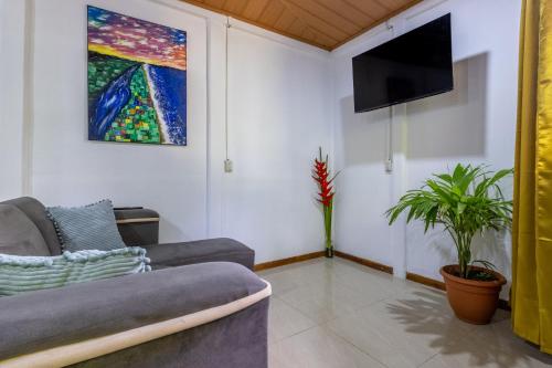 a living room with a couch and a tv at Casa kattleya in Tortuguero