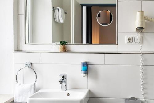bagno bianco con lavandino e specchio di Hotel Weidenhof a Ratisbona