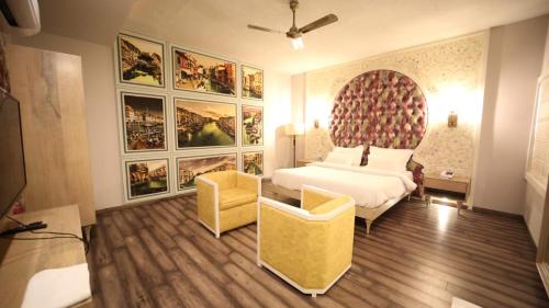 a bedroom with a bed and a couch and paintings at Hotel MEHAI HOUSE in Jaipur