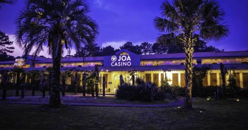 a building with palm trees in front of it at night at B&B HOTEL Arcachon Gujan-Mestras in Gujan-Mestras