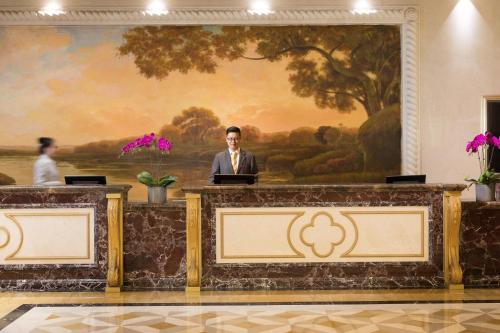 a man standing at a desk in a room with a painting at Crowne Plaza Ocean Spring Resort by IHG in Jimo