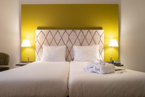 a bedroom with a large white bed with two lamps at Hotel Au Quartier in Maastricht