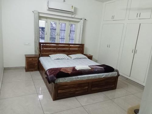 1 dormitorio con cama de madera y ventana en The Olive Greens en Pāonta Sāhib