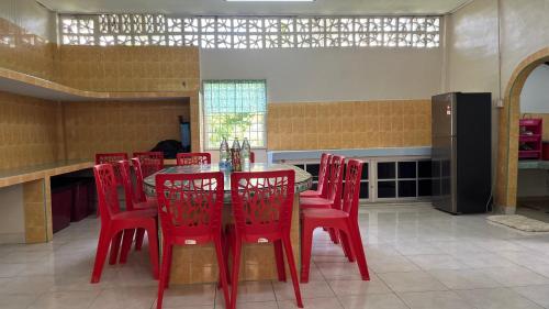 cocina con mesa roja y sillas rojas en Homestay MYZARAH en Pasir Puteh