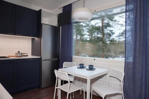 Easypass Apartmenthotel في هلسنكي: مطبخ مع طاولة بيضاء وكراسي ونافذة