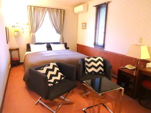 a hotel room with a bed and two chairs at IZUNA INN & SPA - the veggie delights in Ito