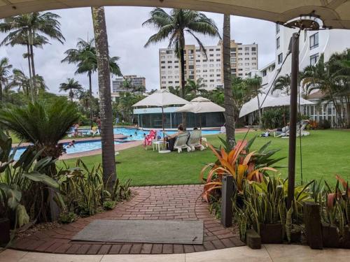 a resort with a pool and palm trees and people at Breakers Resort, Umhlanga in Durban